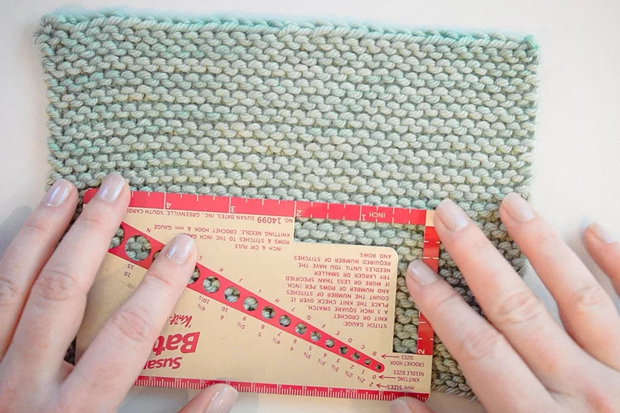 Measuring the stitch gauge of a garter stitch swatch before blocking. Known as the working gauge swatch
