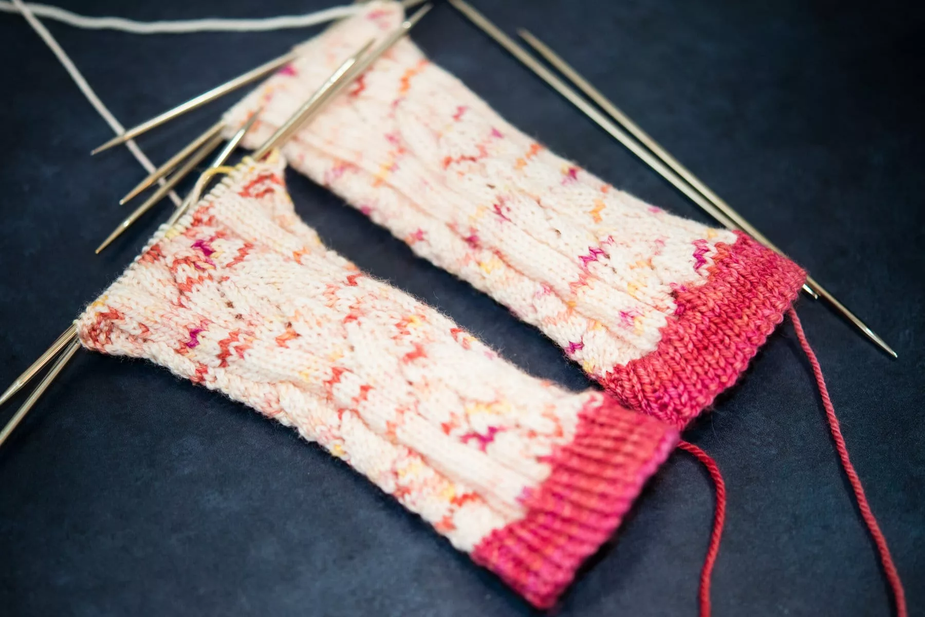 The cuff and legs of Hele Socks, knit in a pink and white Sock Kit called Rose Canyon