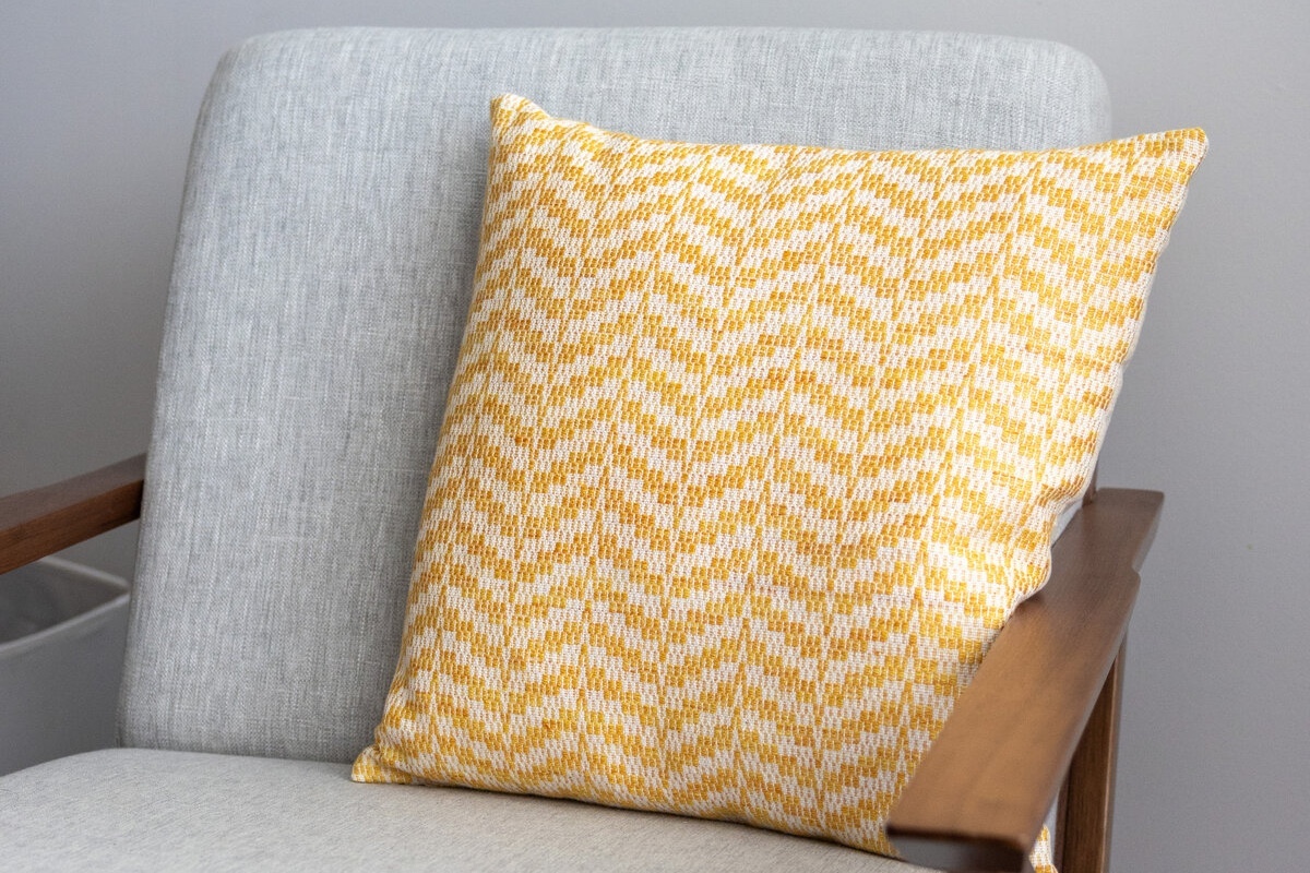 Hello Sunshine Pillow crackle weaving sitting on a linen coloured chair