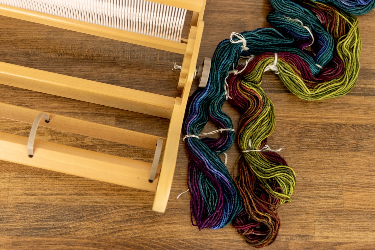 A colourful warp beside a rigid heddle loom