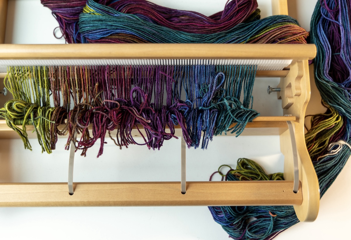 a colourful warp is tied to the front rod of a rigid heddle loom.