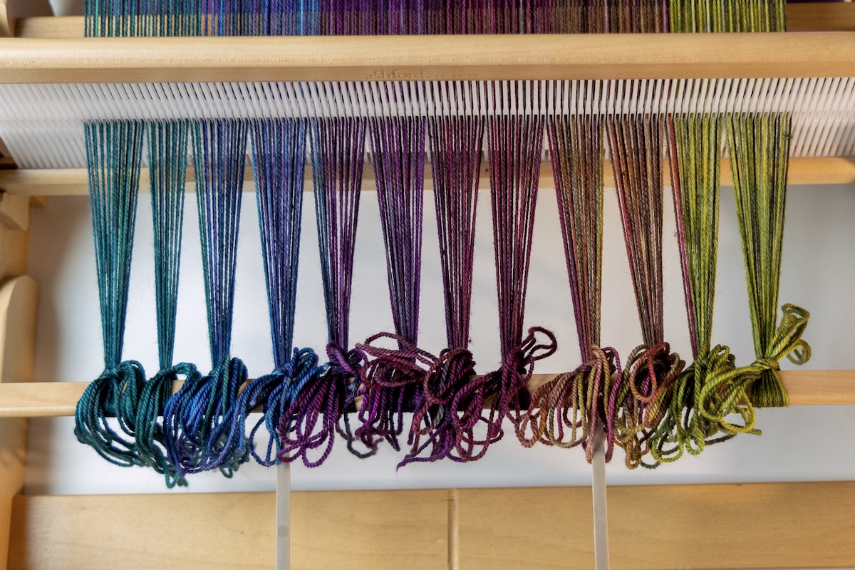 All warp ends are tied to the front rod with even tension.