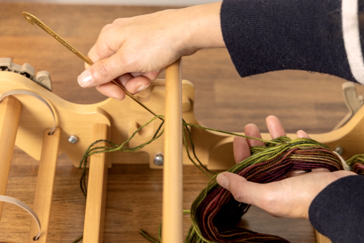 Someone is threading the slots and holes of a rigid heddle.
