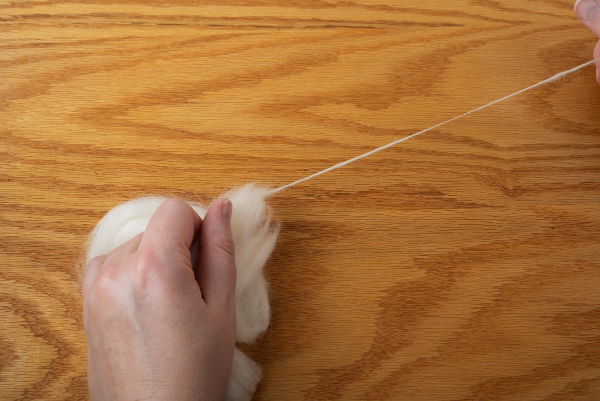 Fibre being pulled and spun by hand