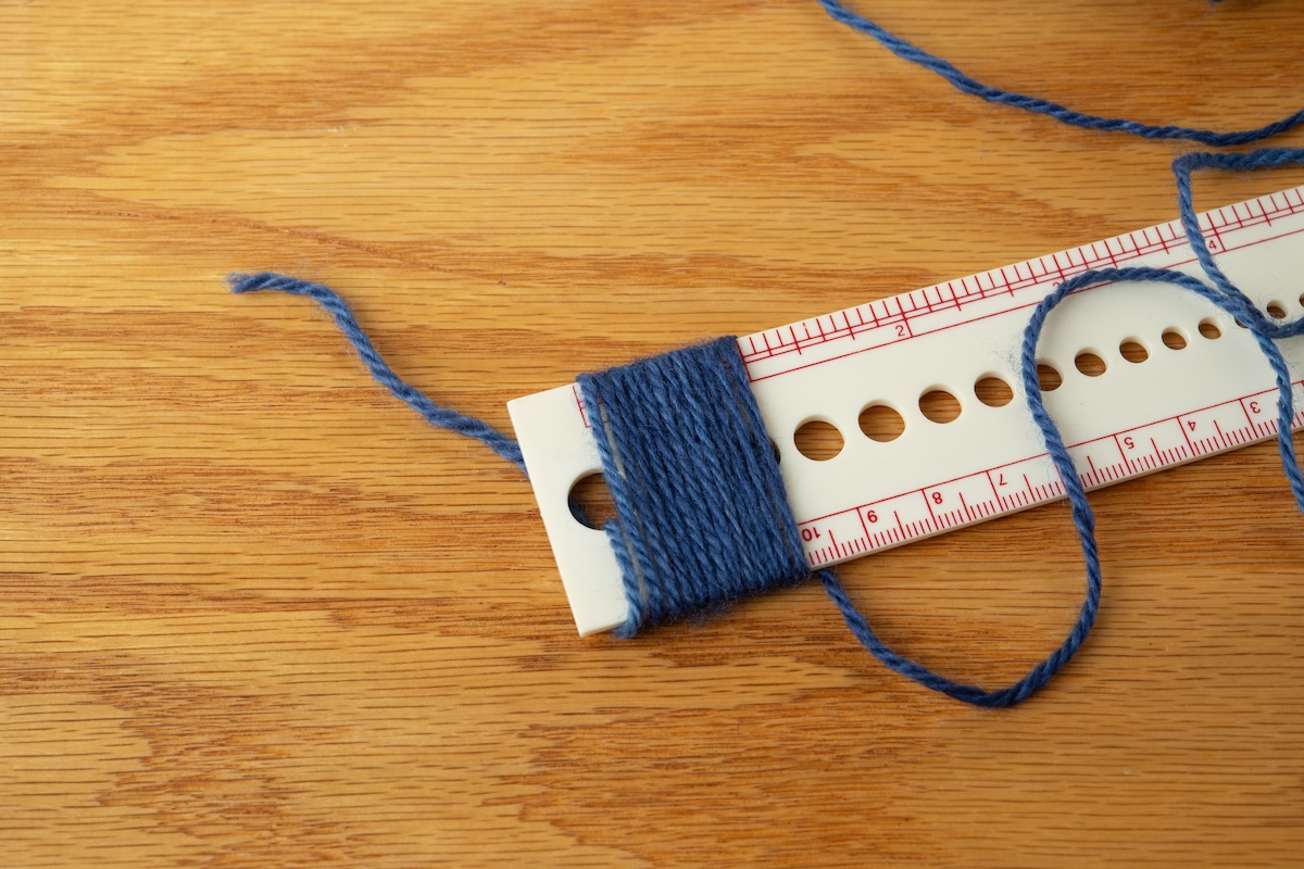 Checking the yarn's wraps per inch. 