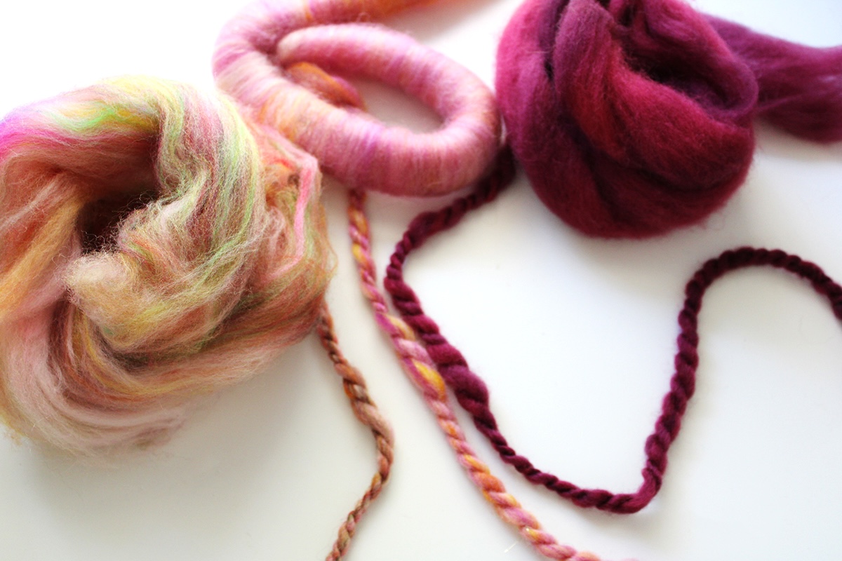 three stands of handspun with the fibre prep behind it