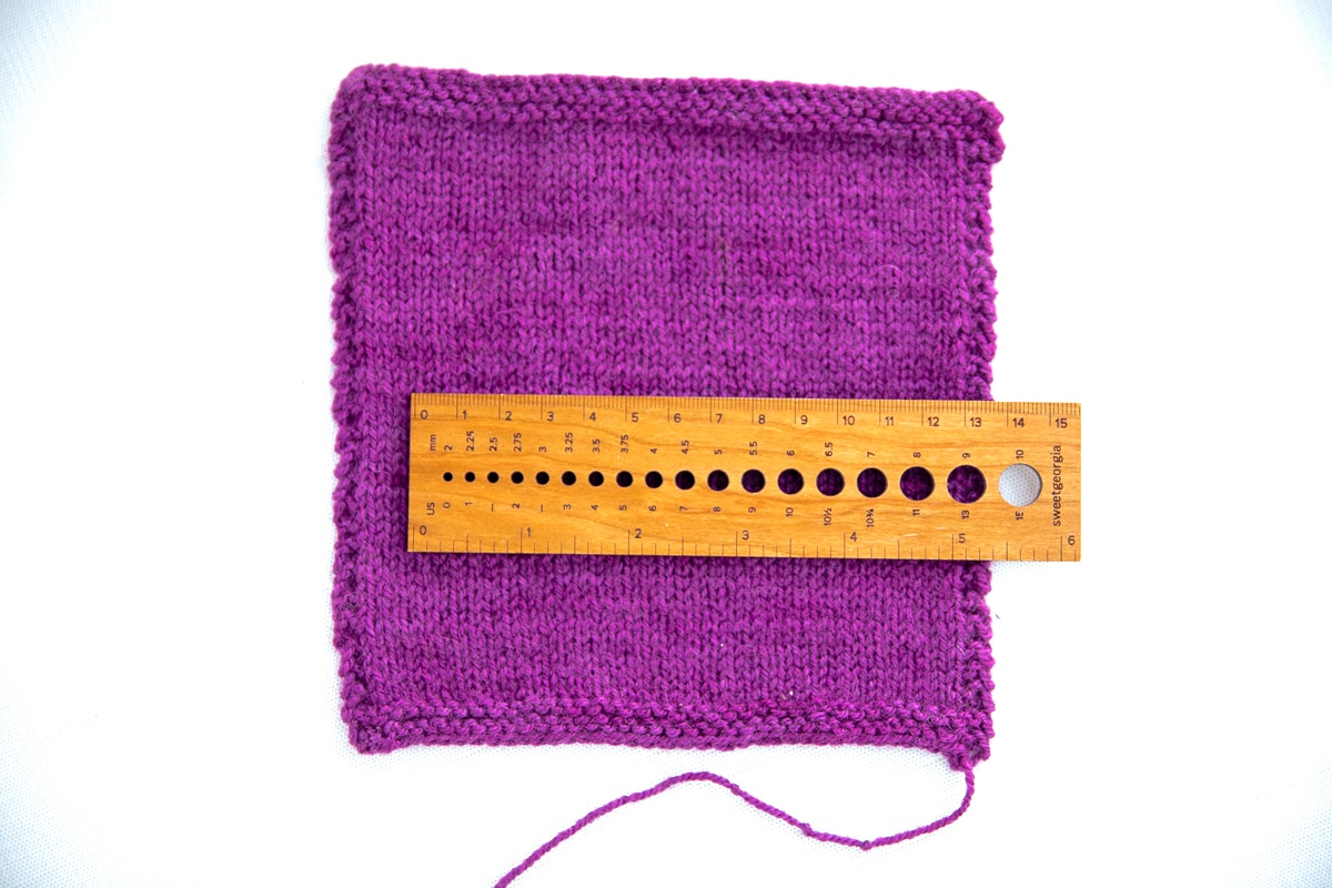 Measuring a swatch knit with SweetGeorgia BFL+Silk Fine using a wooden gauge tool in both Imperial and Metric.