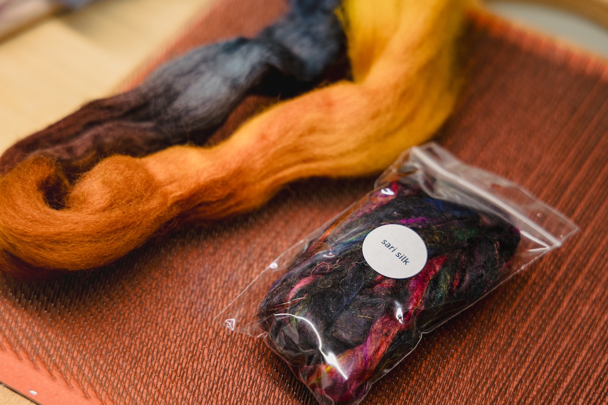 Spinning fibre plus sari silk mix-ins ready to make rolags on a blending board
