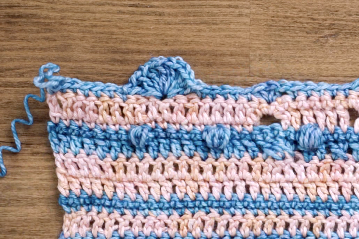 In this example, we see five double crochets (DC) with chain stitches worked between each one, creating a large, spherical fan shape.