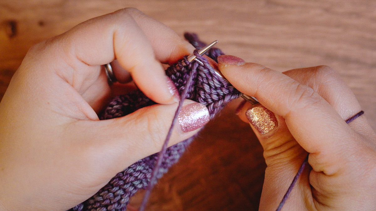 Move the tip of the right needle back through the stitch to create the new purl stitch.